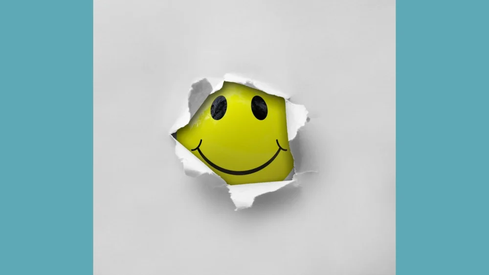 A képen egy nevetős fejecske látszik, egy résen keresztül kukucskál.